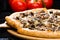 selective focus on sliced piece of appetizing Italian cheese pizza with marinated mushrooms on wooden board on dark background