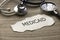 Selective focus of stethoscope, magnifying glass and piece of paper written with Medicaid on wooden background