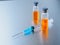 Selective focus. Syringe for injection and two ampoules of coronavirus vaccine and on a silvery aluminum background