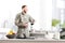 Selective focus of table with fruit bowl, milk bottle, notebook and pen, army soldier pouring filtered coffee in kitchen