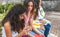 Selective focus of a teenage Latina woman looking at her friend with her cell phone together with another group of girlfriends