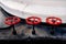 Selective focus on three red painted iron wheels on black ship deck. Industrial shipping objects.