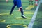 Selective focus to kid soccer player Jogging and jump at ring ladder marker on green artificial turf
