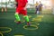 Selective focus to kid soccer player Jogging and jump at ring ladder marker on green artificial turf