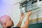 Selective focus to left hand of male technician cleaning air conditioner indoors with a lot of dust