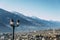 Selective focus of traditional lamppost and dining set table overlooking Sondrio, an Italian town and comune located in the heart