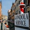 Selective focus on traditional red and white poles advertising Gondola Services in Venice.