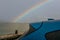 Selective focus on trunk of blue luxury SUV car with raindrops on rainbow and stormy sky background. Car parked at outdoor car