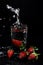 Selective focus vertical shot of a strawberry being dropped into water and causing a splash