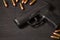 Selective focus view of black pistol and bullets on black wood background