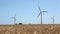 Selective focus view at windmills producing energy in golden wheat fields