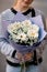 selective focus on white flowers gerbera chrysanthemum and chamomile in wrapping paper in female hands.