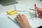 Selective focus on white keyboard of desk top with blurred motion of hands spinning the pencil in foreground with notepad and