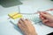 Selective focus on white keyboard of desk top with blurred motion of hands spinning the pencil in foreground with notepad and