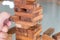 Selective focus at wood brick. Business people using hand to pull out wood brick with caution. taking risk and make decision to