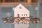 Selective focus at wooden house mock up that put on the top of growth money coins stack on the glass table with blurred background