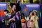 Selective focus on young Asian woman dressed as witch smiling and holding drink at Halloween party with group of friends