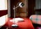 Selective focused shot of a gray and white articulated desk lamp on a red table