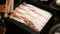 selective focusing close up to tray of beef slice while using chopstick pickup ingredient a piece of raw beef sliced from tray to