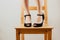 Selective shot of white woman`s legs in black high heeled shoes standing on a wooden chair.