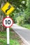 Selective speed limit traffic sign 10 and winding road caution symbol for safety drive in country road in mountain view forest