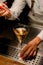 selective view of glass with drink in which woman bartender adds drop of ingredient