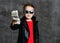 Self-confident rich kid boy in sunglasses, leather jacket and red t-shirt handing us a bundle stack of money cash