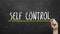 Self control concept. Hand with yellow marker writing self control inscription text on chalkboard.