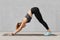 Self determined fitness woman does sport exercises on mat in gym, stands on hands, dressed in tanktop and leggings, poses against