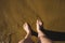 Self photo of the feet on the sand of a beach, waves coming towards the feet