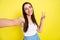 Self-portrait of attractive cheerful girl showing v-sign rest good day isolated over vibrant yellow color background