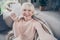 Self-portrait of attractive cheerful grey-haired woman sitting on divan having fun good mood in house flat living-room