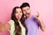 Self-portrait of beautiful friends friendship trendy funky couple embracing grimacing showing horn isolated over pink