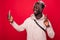 Self-portrait of nice handsome african man beaming smile showing gesture peace isolated over red background