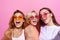 Self portrait of three funny, funky, emotional, expressive, pretty girls, gesture posing on pink background, celebrating