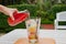 Self pouring ice tea serve with ice cube with fruits frozen inside on a wooden plate and table