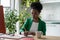 Self-sufficient African American woman working from home office sits at table with computer