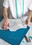 A self-taught seamster in white t-shirt works with fabric, pattern and chalk. A male DIY-designer transfers a template to fabric