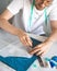 A self-taught tailor in white t-shirt and glasses works with fabric, pattern and chalk. A male designer transfers a template to