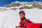 Selfi male mountaineer in snowy mountains, wearing a helmet with a backpack