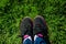 Selfie of female feet on black sneakers standing on green grass