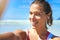 Selfie, fitness and woman with earphones for music and exercise motivation, smile at beach and nature with blue sky
