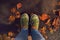 Selfie legs close-up in blue jeans and green sneakers standing in a puddle with yellow leaves in autumn in the park