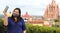 Selfie with mobile phone of Latina tourist woman with protection mask on terrace with cathedral view in San Miguel de Allende, Gu