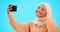 Selfie of muslim woman isolated on blue background for social media kiss, smile and emoji post online. Face of happy