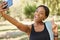 Selfie, peace and park with a sports black woman taking a photograph outdoor during fitness or exercise. Social media