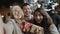 Selfie portrait of group of teenagers smiling and having great time on christmas eve outside. Girls kissing guy friend