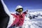 Selfie snowboarder. Young happy woman taking selfie with the smartphone on the top of the North Alps, France.