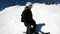A selfie wide angle male skier aged in black equipment and white helmet rides on a snowy slope on a sunny day. The