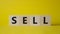 Sell symbol. Concept word Sell on wooden cubes. Beautiful yellow background. Business and Sell concept. Copy space